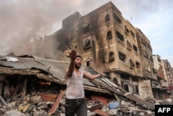 Čovjek ispred srušene zgrade u plamenu, posijle izraelskog bombardovanja grada Gaze, 11. oktobra 2023.