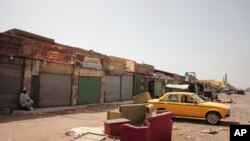 FILE - A man sits by shuttered shops in Khartoum, Sudan, Monday, April 17, 2023. Sudan's embattled capital has awoken to a third day of heavy fighting between the army and a powerful rival force for control of the country.