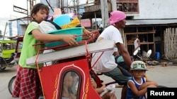 Residents with their belongings ride on a tricycle cab to an evacuation center in Tacloban city, central Philippines, Dec. 4, 2014. 