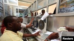 FILE - Workers serve customers at a money transfer office in Soobe village, southern Mogadishu, Somalia, May 8, 2013.