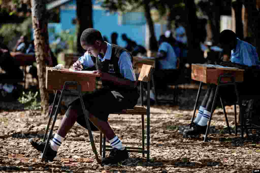 Students of St. Dominic Bukna secondary school take their English test outside due to their overcrowded class room in Kisumu, Kenya.