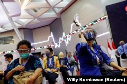 Para perempuan bereaksi saat menunggu dalam masa observasi setelah menerima vaksin Sinovac saat program vaksinasi massal COVID-19 di Bursa Efek Indonesia di Jakarta, 31 Maret 2021. (Foto: REUTERS/Willy Kurniawan)