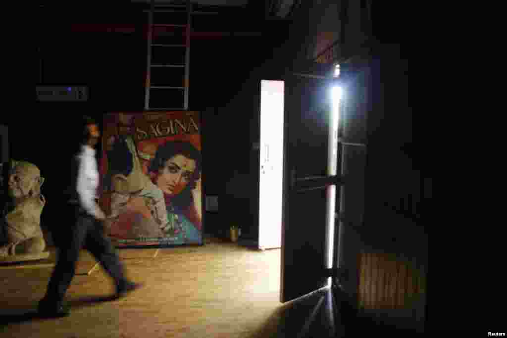 A security guard walks past a Hindi movie poster at an auditorium during a festival celebrating 100 years of Indian cinema in New Delhi, April 30, 2013.