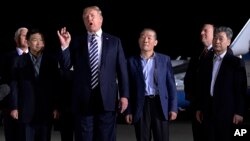 President Donald Trump speaks as he stands with Tony Kim, second left, Kim Dong Chul, center right, and Kim Hak Song, right, three Americans detained in North Korea for more than a year, after they arrived at Andrews Air Force Base in Md., May 10, 2018. 