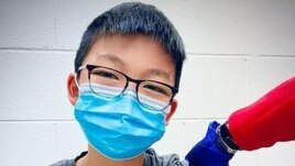 In this Dec. 22, 2020, photo, provided by Richard Chung, his son Caleb Chung receives the first dose of Pfizer coronavirus vaccine or placebo as a trial participant for kids ages 12-15, at Duke University Health System in Durham, N.C. (Richard Chung via AP)