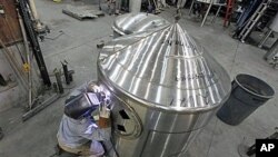 A workman welds a tank at JV Northwest, which manufactures stainless steel vessels, in Camby, Oregon, February 13, 2012.