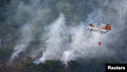 A U.S. military helicopter fights the fire following a crash by another U.S. military CH-46 helicopter, inside Camp Hansen in central Okinawa, on Japan's southern island, in this photo taken by Kyodo, Japan, August 5, 2013. 