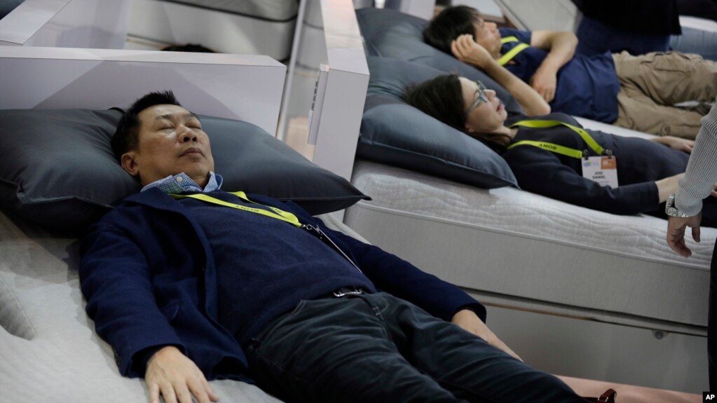 FILE - People try out smart beds during CES International, Saturday, Jan. 7, 2017, in Las Vegas. The bed has sensors that adjust the comfort and firmness depending on the user's position. It also warms the foot area prior to bedtime and it can sense snori