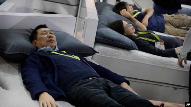 FILE - People try out smart beds during CES International, Saturday, Jan. 7, 2017, in Las Vegas. The bed has sensors that adjust the comfort and firmness depending on the user's position. It also warms the foot area prior to bedtime and it can sense snori