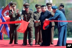 North Korean leader Kim Jong Un, fourth right, stands with officials as he cuts the ribbon at the official opening of the Ryomyong high-rise district, Thursday, April 13, 2017, in Pyongyang, North Korea.