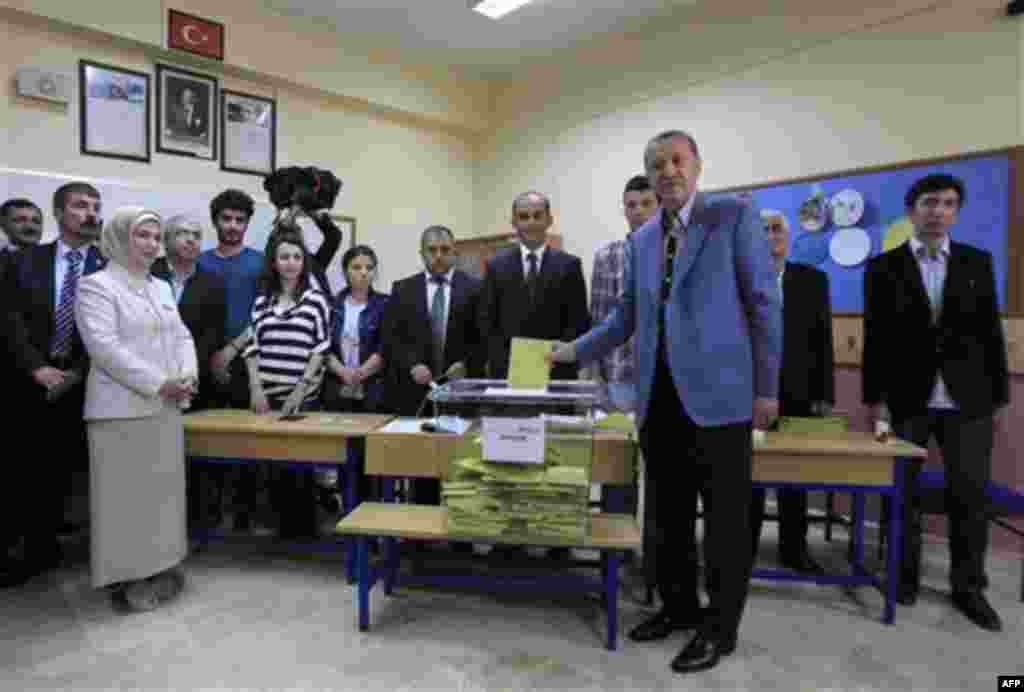 Turkish Prime Minister Recep Tayyip Erdogan casts his ballot as his wife Emine, left, looks on at a polling station in Istanbul, Sunday, June 12, 2011. Turkey's ruling party sought a third term in elections Sunday, aiming to build on economic and diplomat