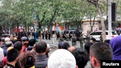 Warga menyaksikan polisi mengosongkan jalanan setelah ledakan di Urumqi, Xinjiang (22/5).