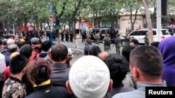 Des gens se rassemblent près d'une rue fermée par la police après une explosion à Urumqi, dans la région autonome ouïghoure du Xinjiang, le 22 mai 2014.