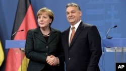 Hungarian Prime Minister Viktor Orban (r) and German Chancellor Angela Merkel shake hands after their news conference in the Parliament building in Budapest, Feb. 2, 2015.