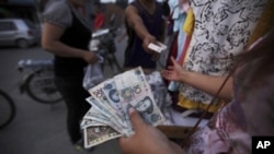 A Chinese woman, who sells clothes on the roadside, holds tens of Yuan, while dealing with a customer, in a Hutong, or a traditional alleyway, in Beijing, China, 22 Jun 2010