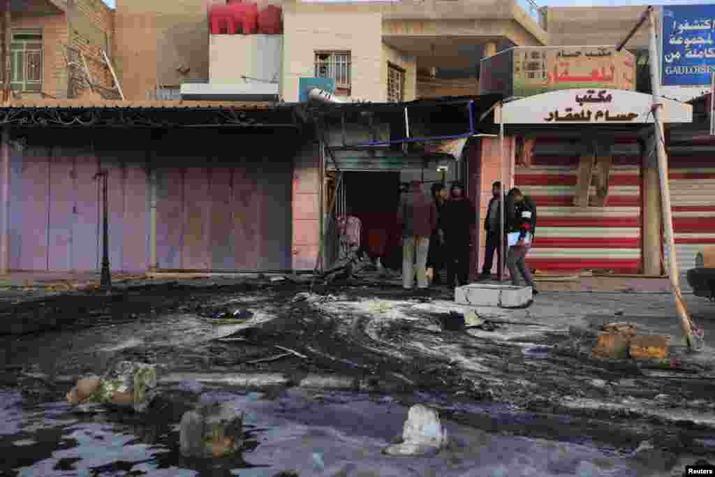 Warga melihat lokasi serangan bom di distrik Ghazaliya, Baghdad (15/1).