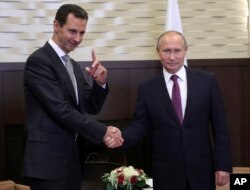 Presiden Rusia Vladimir Putin (kanan) berjabat tangan dengan Presiden Suriah Bashar Assad di Kota Sochi, kota tetirah di Laut Hitam, Rusia, 20 November 2017.