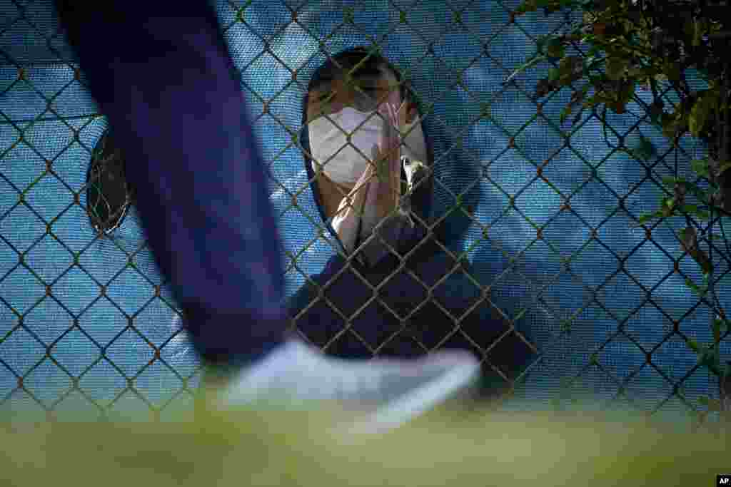 A fan wearing a face mask cheers through a hole in the fence as a golfer leaves the 12th tee during the second round of the PGA Championship golf tournament at TPC Harding Park in San Francisco.