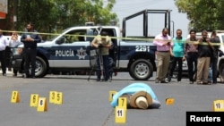 Evidence identifiers are placed next to the body of journalist Javier Valdez at a crime scene in Culiacan, Mexico, May 15, 2017.
