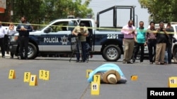 Evidence identifiers are placed next to the body of journalist Javier Valdez at a crime scene in Culiacan, Mexico, May 15, 2017.