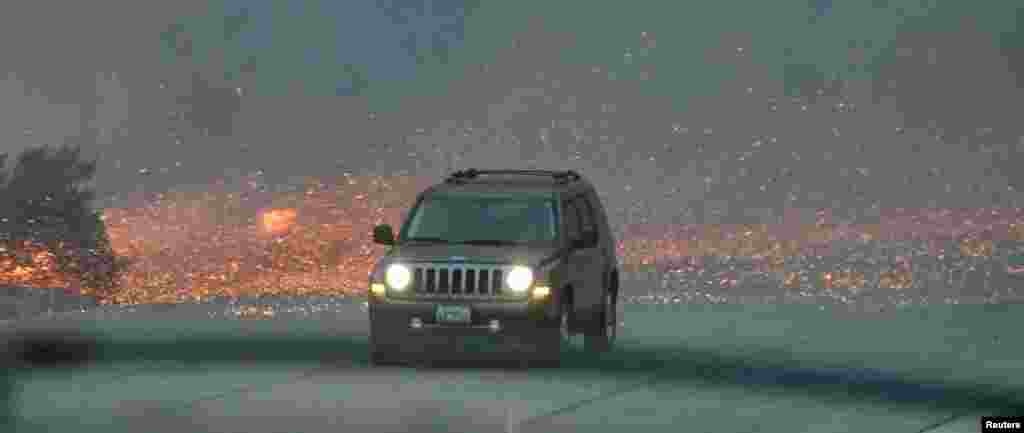 A vehicle drives through the flying embers from heavy winds after an early-morning Creek Fire that broke out in the Kagel Canyon area in the San Fernando Valley north of Los Angeles, in Sylmar, Dec. 5, 2017.