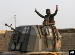 A member of Iraq's elite counterterrorism forces in a military convoy flashes a victory sign as forces advance toward Islamic State positions in the village of Tob Zawa, about 9 kilometers (5½ miles) from Mosul, Iraq, Oct. 25, 2016.