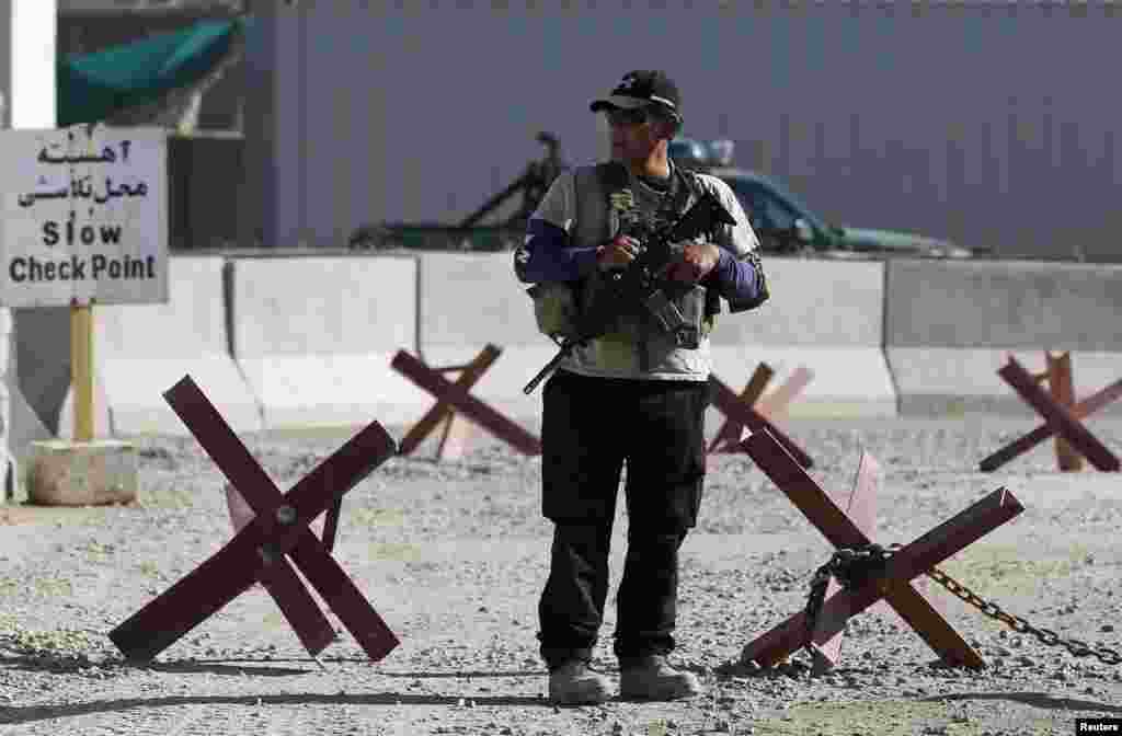 A foreign security contractor keeps watch at the site of a suicide attack, outside the counter-narcotics office near the Kabul International Airport, July 22, 2014.&nbsp;