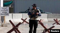 FILE - A foreign security contractor keeps watch at the site of a blast near Afghanistan's Kabul International Airport. 