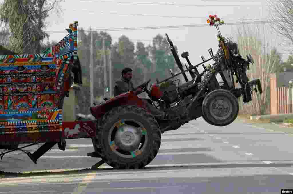 The front wheels of a tractor lift off the ground as the driver moves a heavy trailer outside Peshawar, Pakistan.