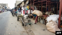 Un grossiste transporte un sac de vêtements de seconde main à son stand du marché de Colobane à Dakar, le 25 juin 2019.