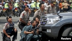 Police officers react near the site of a blast in Jakarta, Indonesia, January 14, 2016. Several explosions went off and gunfire broke out in the centre of the Indonesian capital on Thursday and police said they suspected a suicide bomber was responsible f