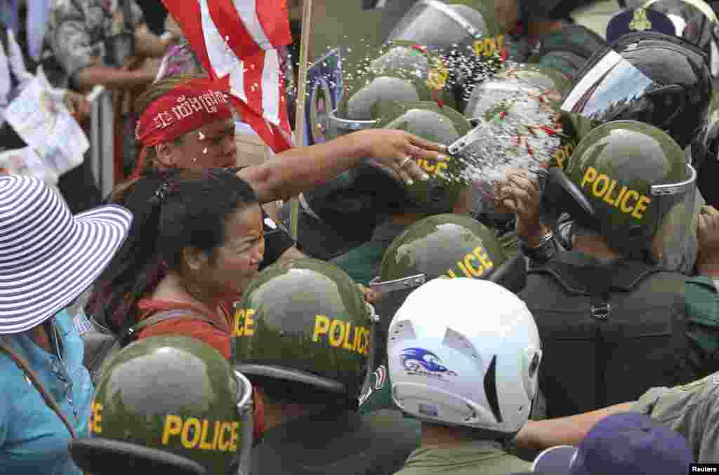 Seorang wanita melempar garam dan cabe ke arah polisi yang memblokir jalan selama protes sengketa tanah di Phnom Penh, Kamboja. 