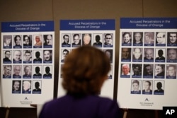 An advocate and survivor of sexual abuse, looks at the photos of Catholic priests accused of sexual misconduct by victims during a news conference, Dec. 6, 2018, in Orange, California.