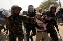 FILE: A worker who had been taking part in a protest is escorted by Cambodian soldiers after clashes broke out, on the outskirts of Phnom Penh January 2, 2014.