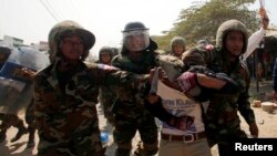 A worker who had been taking part in a protest is escorted by Cambodian soldiers after clashes broke out, on the outskirts of Phnom Penh January 2, 2014. Cambodian soldiers on Thursday broke up the protest by factory workers on strike, who were demanding a doubling of their wages, witnesses and a rights worker said. Around 100 soldiers with riot gear from a nearby base were deployed to move the workers who had been protesting outside their factory about 20km (12 miles) west of the capital Phnom Penh.