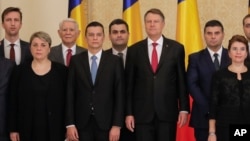 Romanian Prime Minister Sorin Grindeanu, center left, poses for the media next to Romanian President Klaus Iohannis after the swearing in ceremony for his cabinet, in Bucharest, Romania, Jan. 4, 2017.