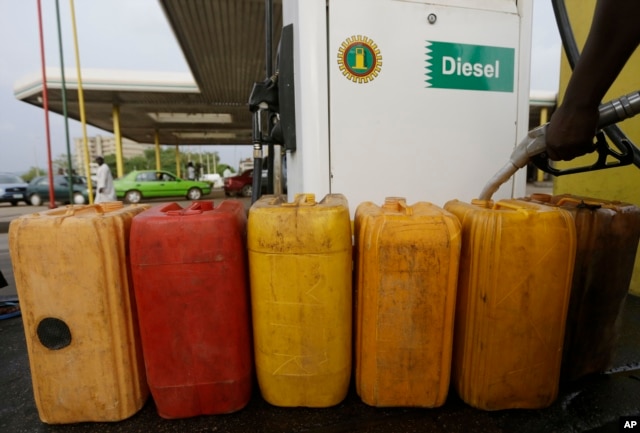 FILE- A man fills containers with diesel at the Nigeria National Petroleum Corporation, petrol station in Abuja, Nigeria, May. 26, 2015.