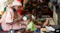 FILE- A mother feeds her malnourished child at a feeding center run by Doctors Without Borders in Maiduguri, Nigeria, Aug. 29, 2016.