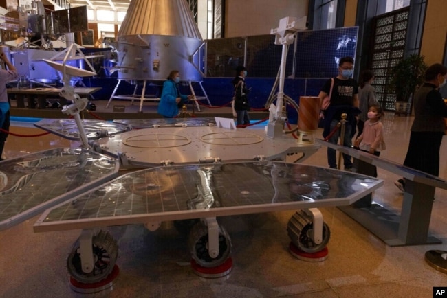 FILE - Visitors to a Chinese space exhibit look at a life-size model of the Chinese Mars rover Zhurong, named after the Chinese god of fire, at the National Museum in Beijing, May 6, 2021. China said May 15 that it had landed a rover on the Red Planet.