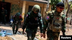 FILE - LT Saw Kaw, seorang prajurit Tentara Pembebasan Nasional Karen (KNLA), berjalan bersama anggota timnya setelah memeriksa rumah seorang pejabat tinggi militer Myanmar di Batalyon Infanteri 275 di Myawaddy, 15 April 2024.