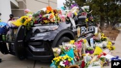 Police cruiser parked outside Boulder Police Department is covered with bouquets in tribute after an officer was one of the victims of a mass shooting at a King Soopers grocery store, March 23, 2021, in Boulder, Colo. 