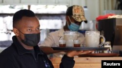 FILE - Deaf waiter Michael Mwangi walks to serve customers amid the COVID-19 pandemic, at the Pallet Cafe in Lavington area of Nairobi, Kenya, August 23, 2021.