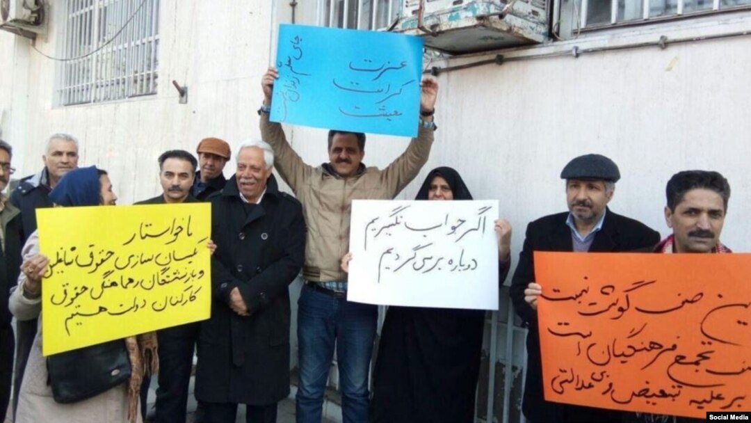 In this image sent to and verified by VOA Persian, Iranian teachers protest in the northeastern city of Mashhad, Feb, 14, 2019. The yellow sign calls for teachers to be paid at equal rates to other public-sector workers, while the blue sign says a teacher’s place isn't in prison.