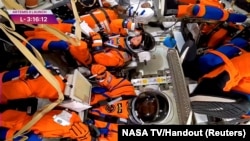 在位于佛罗里达州卡纳维拉尔角的肯尼迪航天中心，“阿尔忒弥斯二号”绕月飞行任务发射前，美国宇航员克里斯蒂娜·科赫在“猎户座”载人飞船舱内调整头盔面罩。在她左手边的是加拿大宇航员杰里米·汉森。(2026年4月1日)