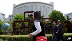 In this April 19, 2019, photo, foreigners pass by the Chinese Foreign Ministry in Beijing, China. China on Wednesday, Feb. 19, 2020 said it has revoked the press credentials of three reporters for the U.S. newspaper Wall Street Journal over a…