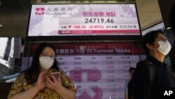 People walk past a bank's electronic board showing the Hong Kong share index at Hong Kong Stock Exchange, Oct. 27, 2020. 