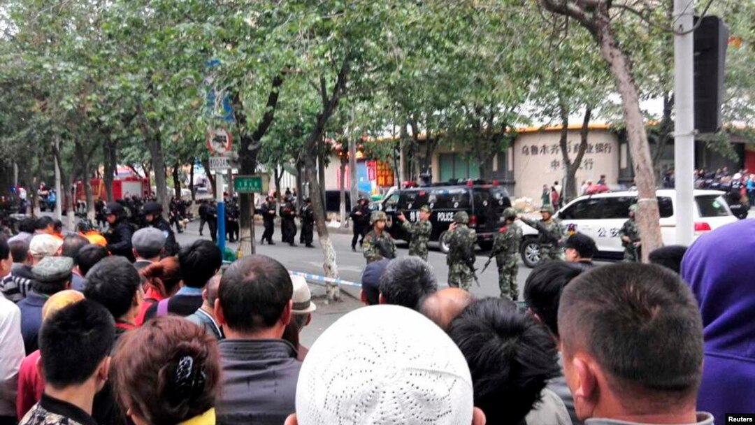 Warga menyaksikan polisi mengosongkan jalanan setelah ledakan di Urumqi, Xinjiang (22/5).