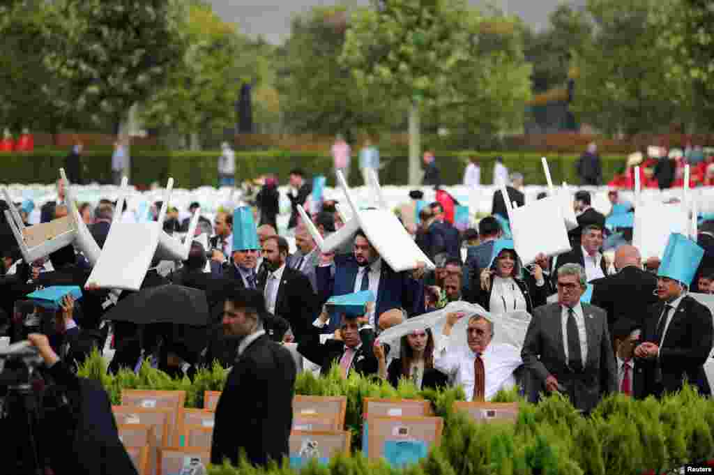 Invitees take cover from the rain as they wait for arrival of Turkish President Tayyip Erdogan during a ceremony at the Presidential Palace in Ankara.