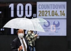Passersby walk past a screen showing a countdown to the Tokyo 2020 Olympic Games and Tokyo 2020 Paralympic Games that have been postponed to 2021 due to the coronavirus disease (COVID-19) pandemic, in Tokyo, Japan, Apr. 4, 2021.