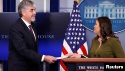 U.S. acting Secretary of Health and Human Services Eric Hargan receives a symbolic check, representing U.S. President Donald Trump's quarterly salary as a donation to the department to fight opioid epidemic, from White House Press Secretary Sarah Huckabe